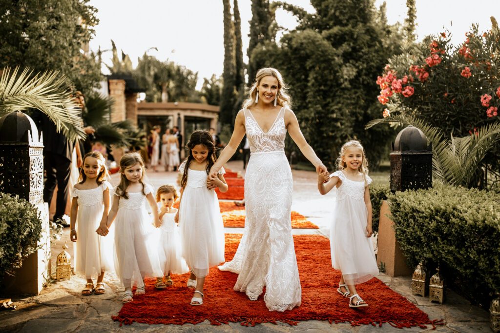 Mariée et enfants d'honneur sur un tapis rouge dans un jardin de Marrakech